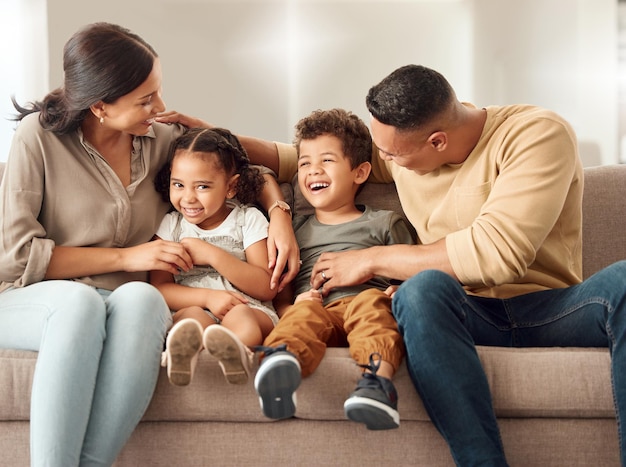 Playful children and parents on the sofa for love care and happiness in the living room of home together Portrait of happy smile and young kids playing with their mother and father on the couch