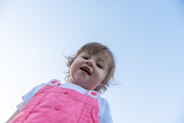 игривая милая маленькая девочка весело проводит время, бегая по просторному заднему двору по траве