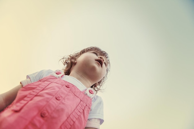 playful cute little girl cheerfully spending time while running in the spacious backyard on the grass