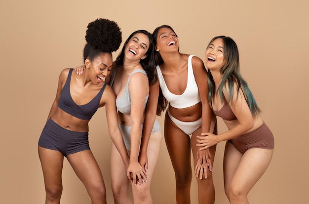 Playful diverse women posing with joy over beige background