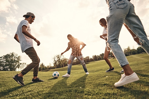 Playful friends. Group of young smiling people in casual wear playing soccer while standing outdoors