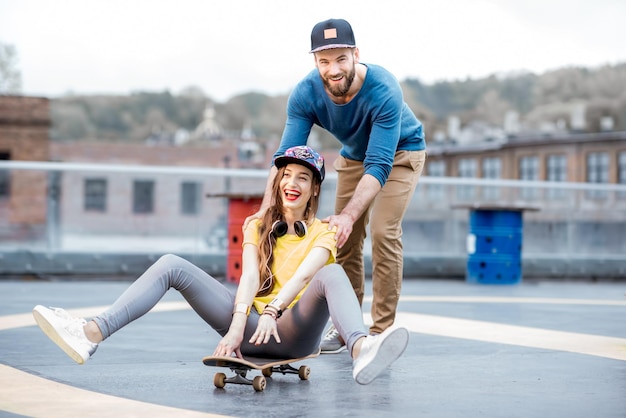 Playful friends having fun skating together on the skateboard outdoors on the playground