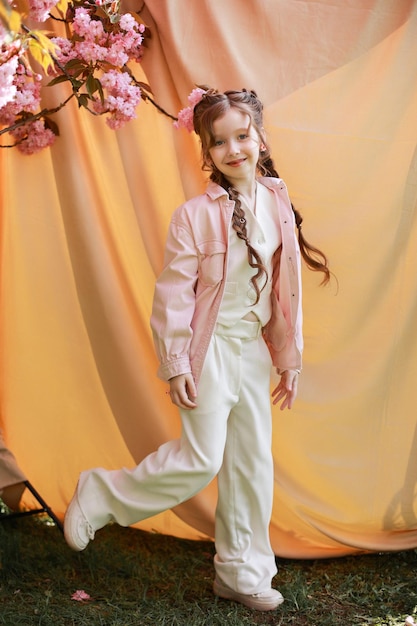 Playful girl in a good mood on a beige background and a branch of blooming sakura