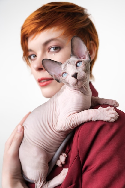 Playful kitten looking up sitting on shoulder redhead woman with short hair Selective focus on cat