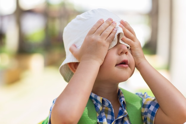 遊び心のある小さな男の子、手で目を覆う