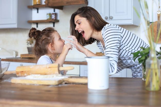 彼女の愛情深い母親と一緒にキッチンで料理をしている遊び心のある少女。