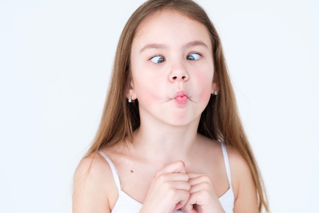 playful mischievous child making faces on white wall.