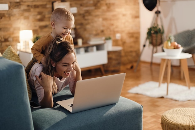 Madre e figlio giocosi che fanno una videochiamata sul laptop a casa