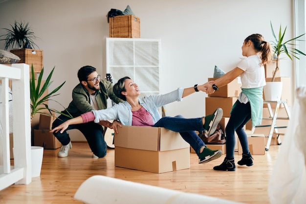 Playful parents and daughter having fun while moving into new house