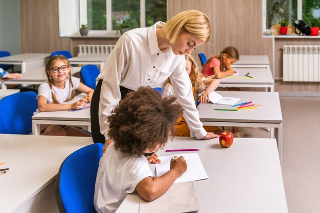 Playful schoolers enjoying school time and lesson with teacher and classmates