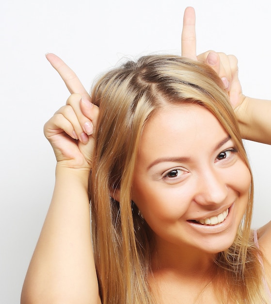 Playful  teen blond girl shows horns