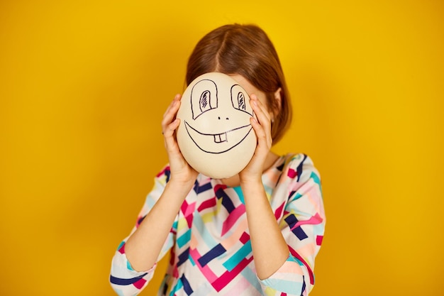 Playful teenager girl covering her face of Ostrich egg with funny face