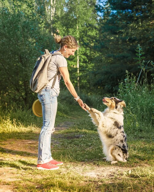 公園を散歩中に幸せな中年の女性に足を与える遊び心のある訓練された雑種犬