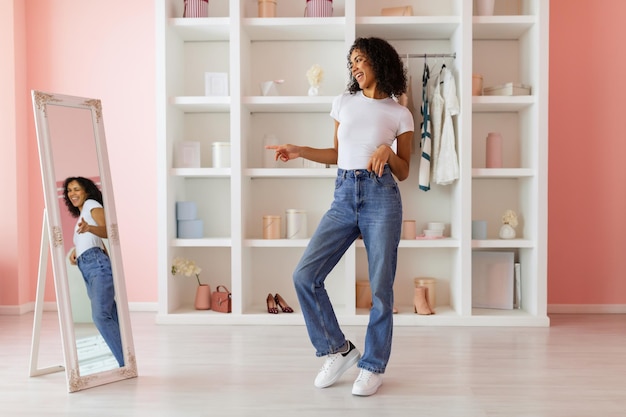 Playful woman dancing in jeans reflection in mirror