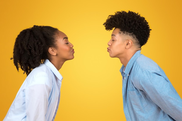 Playful young african american couple giving each other a kissy face with eyes closed