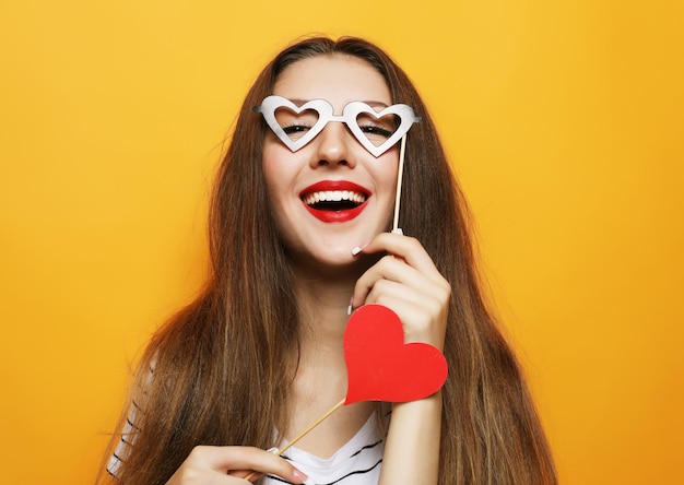 Playful young woman ready for party over yellow background