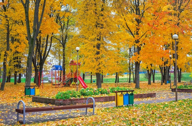 Детская площадка в осеннем парке. Деревья с разноцветными листьями