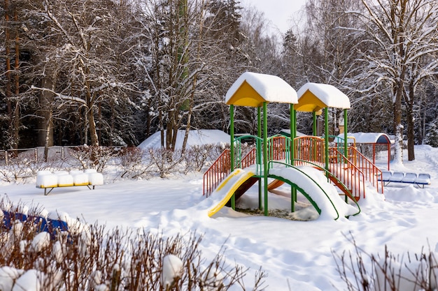 Playground Slide Surrounded by Trees Covered with Snow