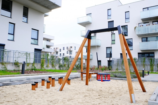 Playground with a children swing in cozy courtyard of modern residential district.