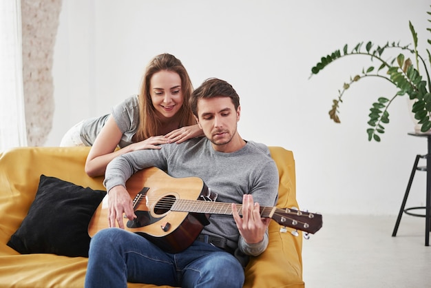 새 집 거실에서 여자 친구를 위해 어쿠스틱 기타 연주.