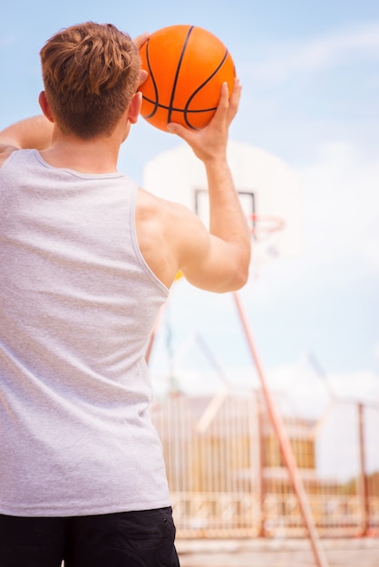 Playing Basketball. Rear view of young male basketball player ready for the shot