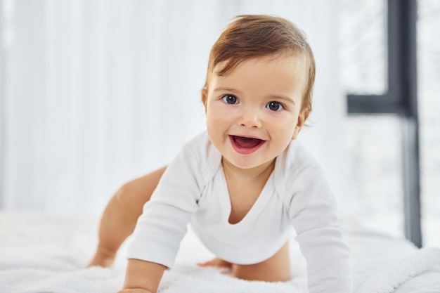 Playing on the bed Cute little baby is indoors in the domestic room