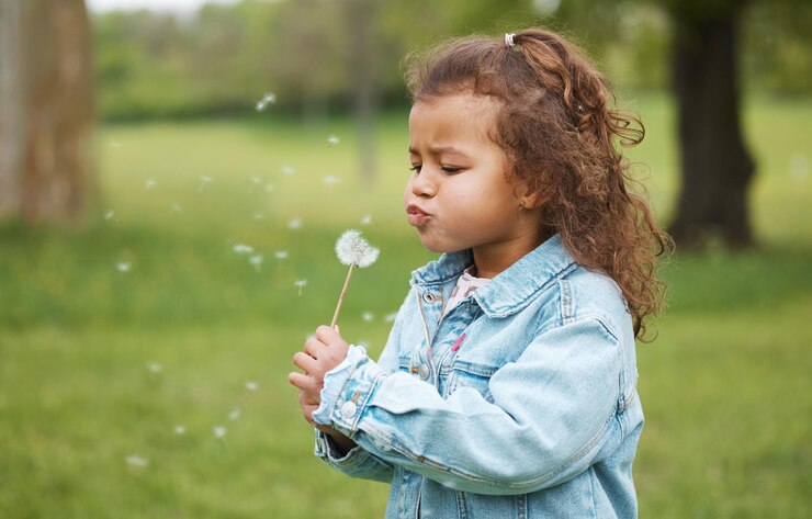 Photo playing blowing plant and child in nature environment exploration and wish on ecology in australia carefree sustainability and girl kid with a dandelion in a park garden or backyard for fun