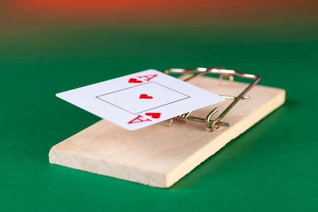 Playing card and mousetrap, game trap, on a green background, get into gambling addiction.