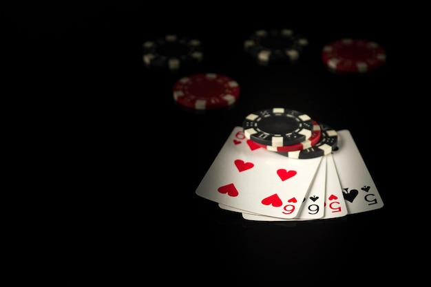 Playing cards on a black table with a two pairs poker winning combination and chips