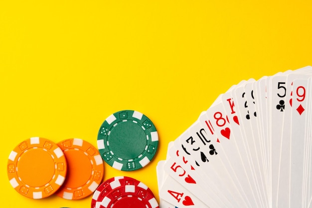 Playing cards and poker chips on yellow background