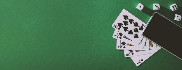 Playing cards poker dice and phone on green blue cloth panorama