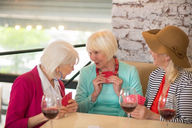 Photo playing cards. senior good-looking cheerful women playing cards and looking enjoyed