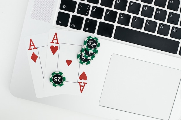 Playing cards with chips on laptop keyboard Online casino concept Top view