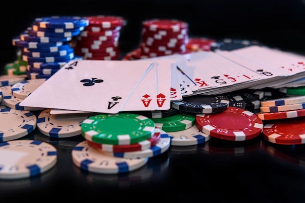 Foto carte da gioco con fiches da poker sulla superficie nera