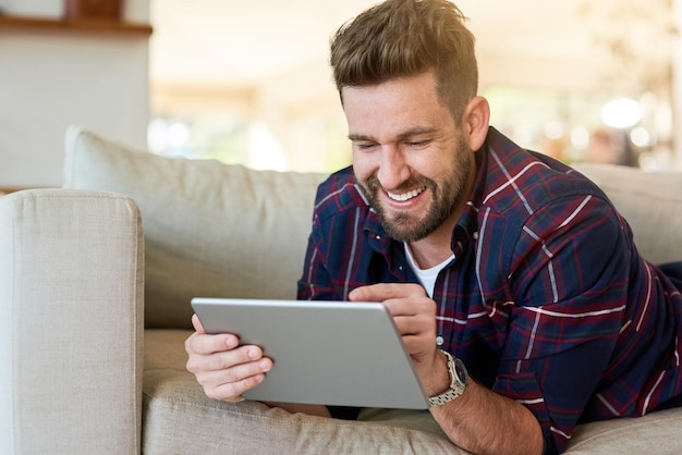 Playing catch up with life online Shot of a relaxed young man using a digital tablet on the sofa at home