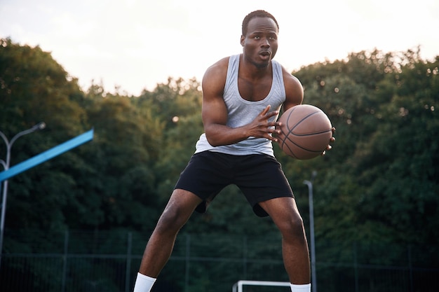 Foto giocando al gioco giovane uomo di colore è con la palla da basket all'aperto