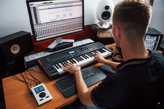 Photo playing midi keyboard. sound engineer working and mixing music indoors in the studio.