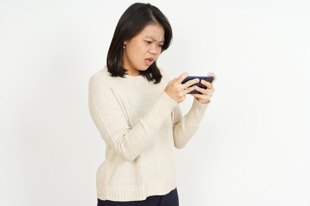 Giocare al gioco per cellulare sullo smartphone della bella donna asiatica isolata su sfondo bianco
