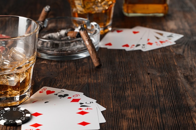 Playing poker with whiskey and cigars on table