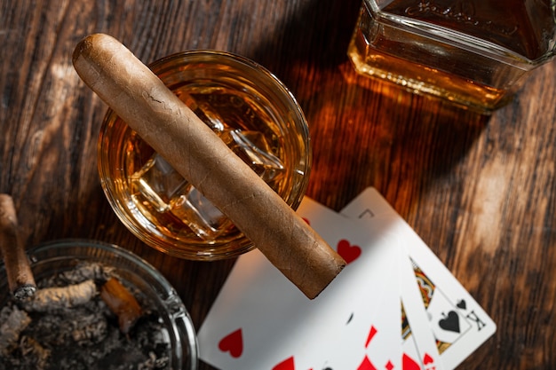 Playing poker with whiskey and cigars on table