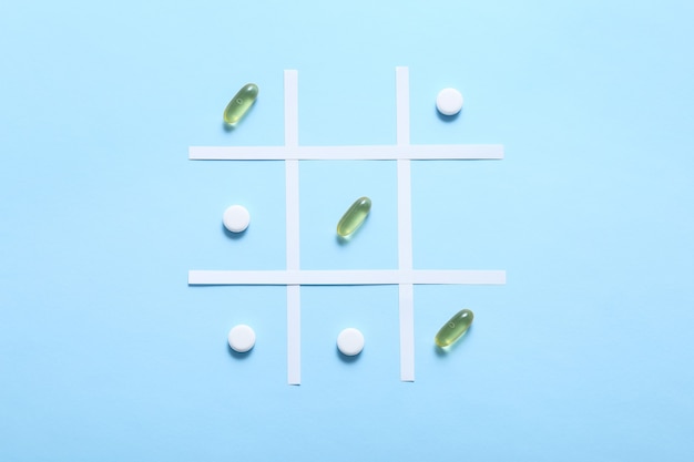 Playing tic tac toe with pills on blue