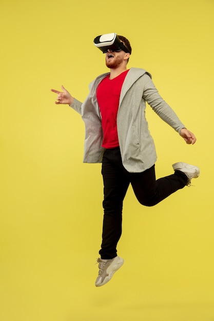 Играя VRheadset Полный портрет молодого человека прыгающего в высоту жесты изолированного