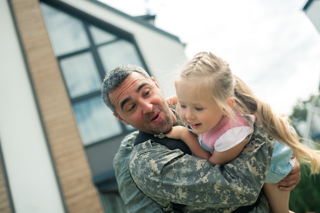 写真 女の子と遊ぶ。彼の女の子と遊んで幸せな気持ちの制服を着たひげを生やした軍の将校