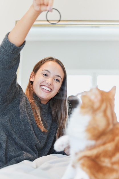 Playing with my cat puts me in the best mood Shot of a young woman playing with her cat at home