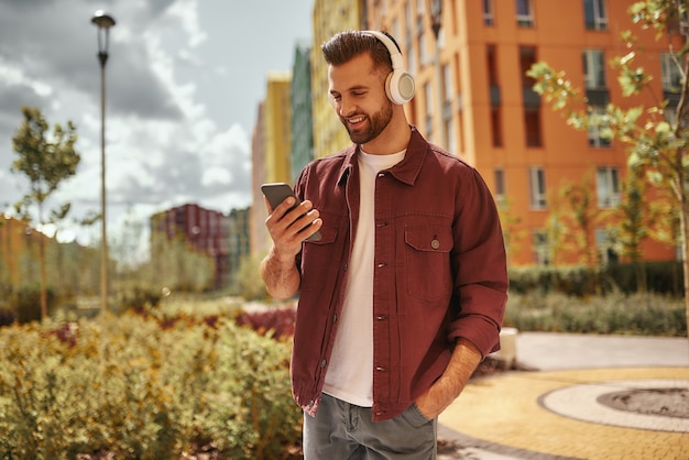 Playlist settings happy young man with stubble in headphones listening to the music and holding