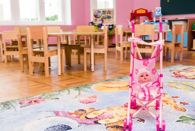 Фото Игровая в детском саду на переднем плане сидит кукла в розовой коляске