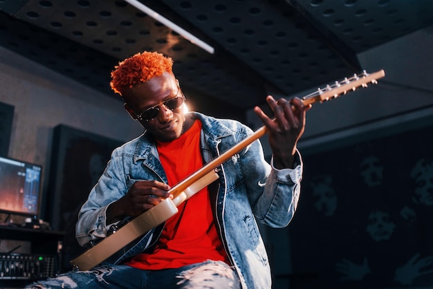 Foto suona la chitarra giovane esecutore afroamericano che prova in uno studio di registrazione