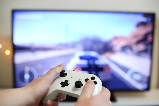 Plays racing games on TV while holding white gamepad