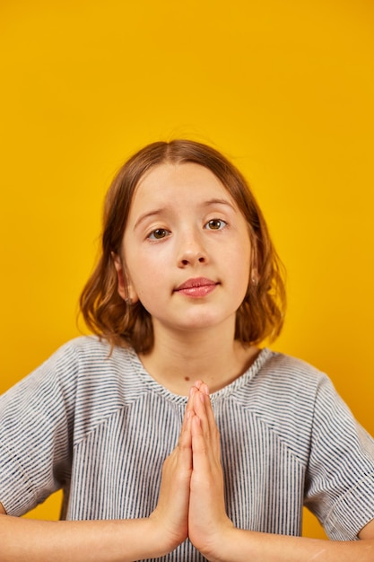 Photo pleading teen girl on yellow studio background wish and praying please sign language positive lifestyle concept