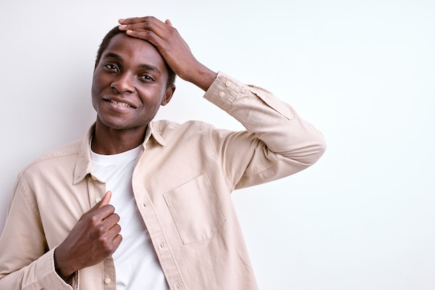 Pleasant afro american guy touching head and smiling isolated on white background